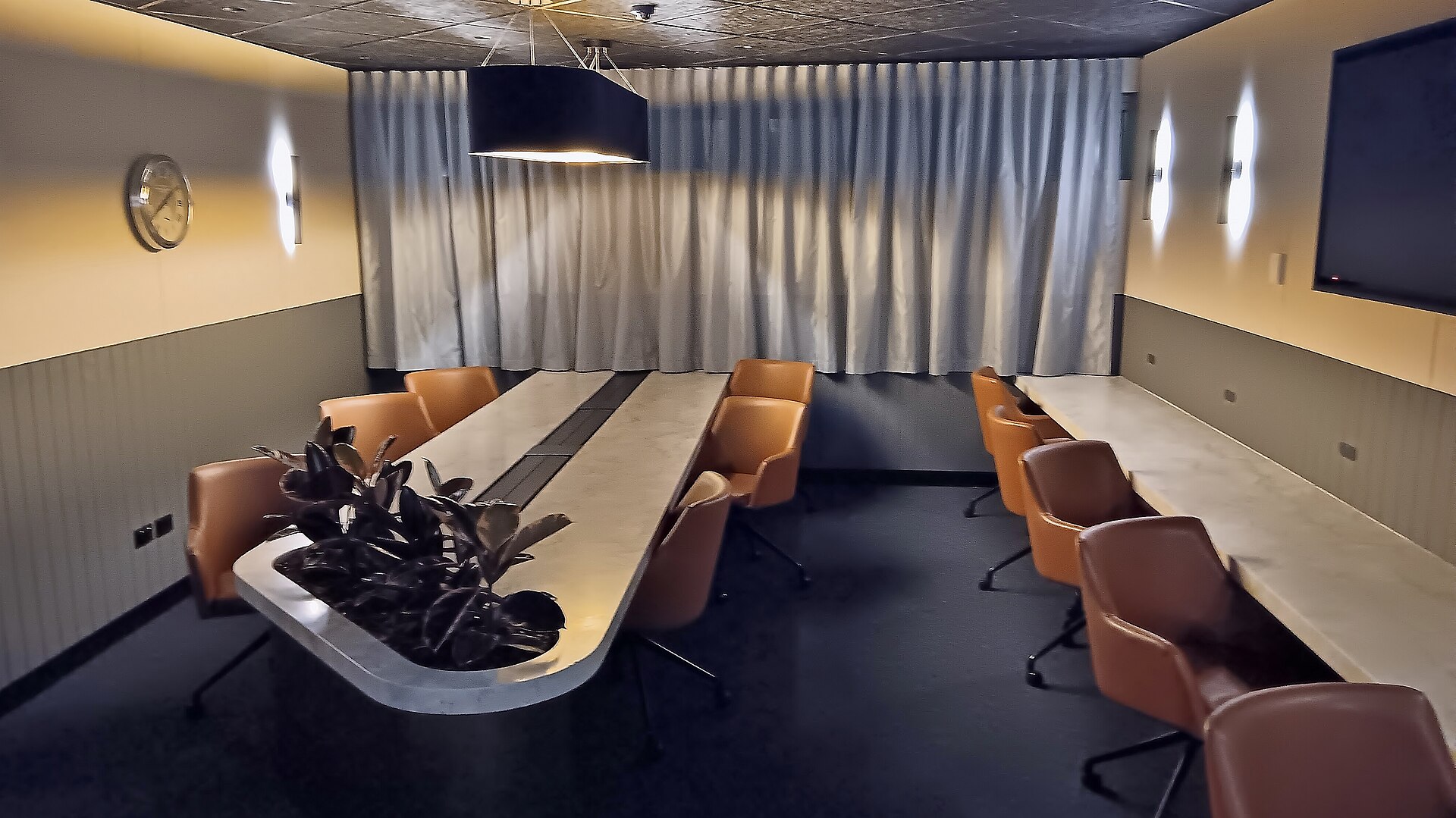 An airport executive lounge with a long shared table and leather chairs