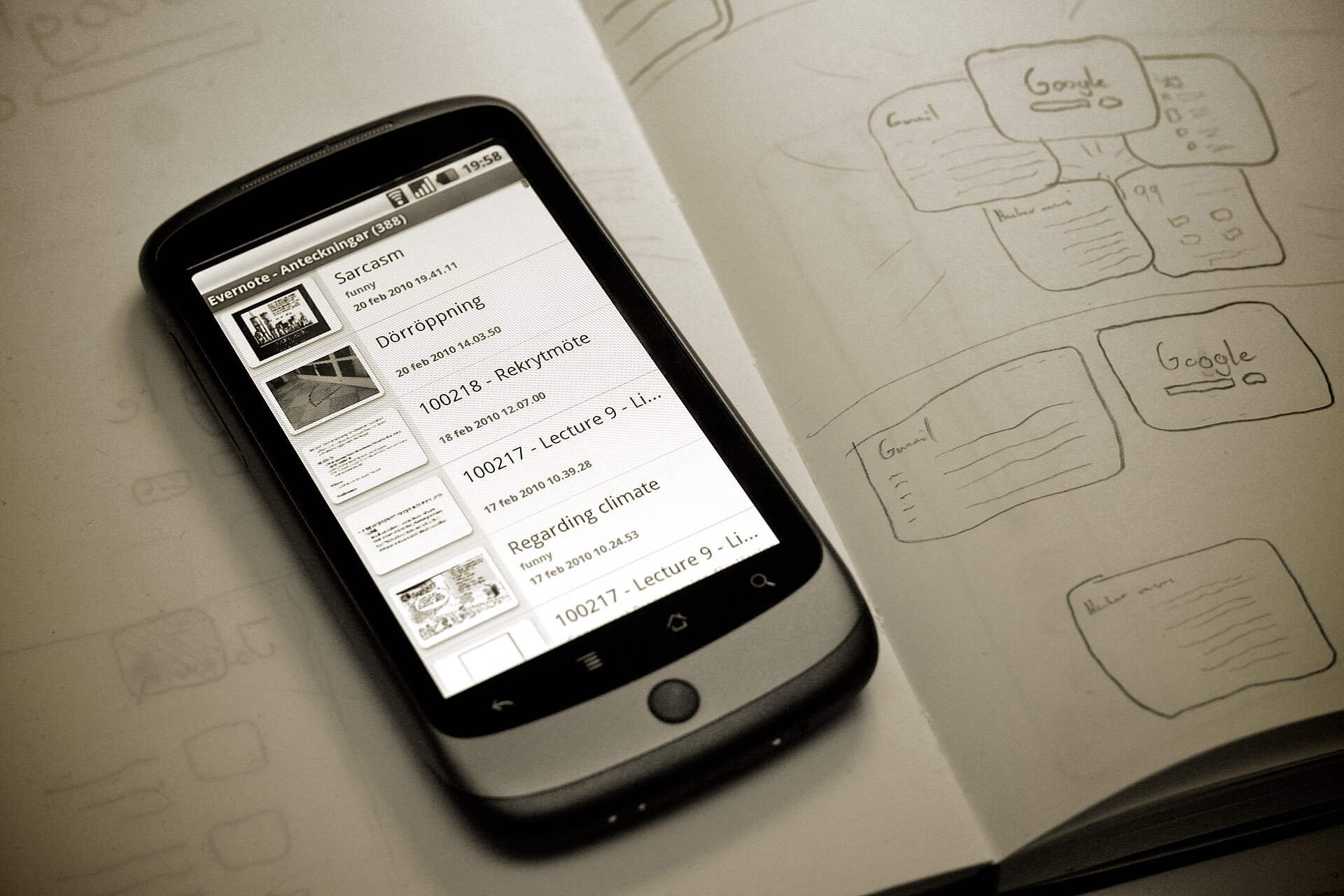 A Nexus One running Android 2.x, lying on a sketchbook of hand-drawn app screens